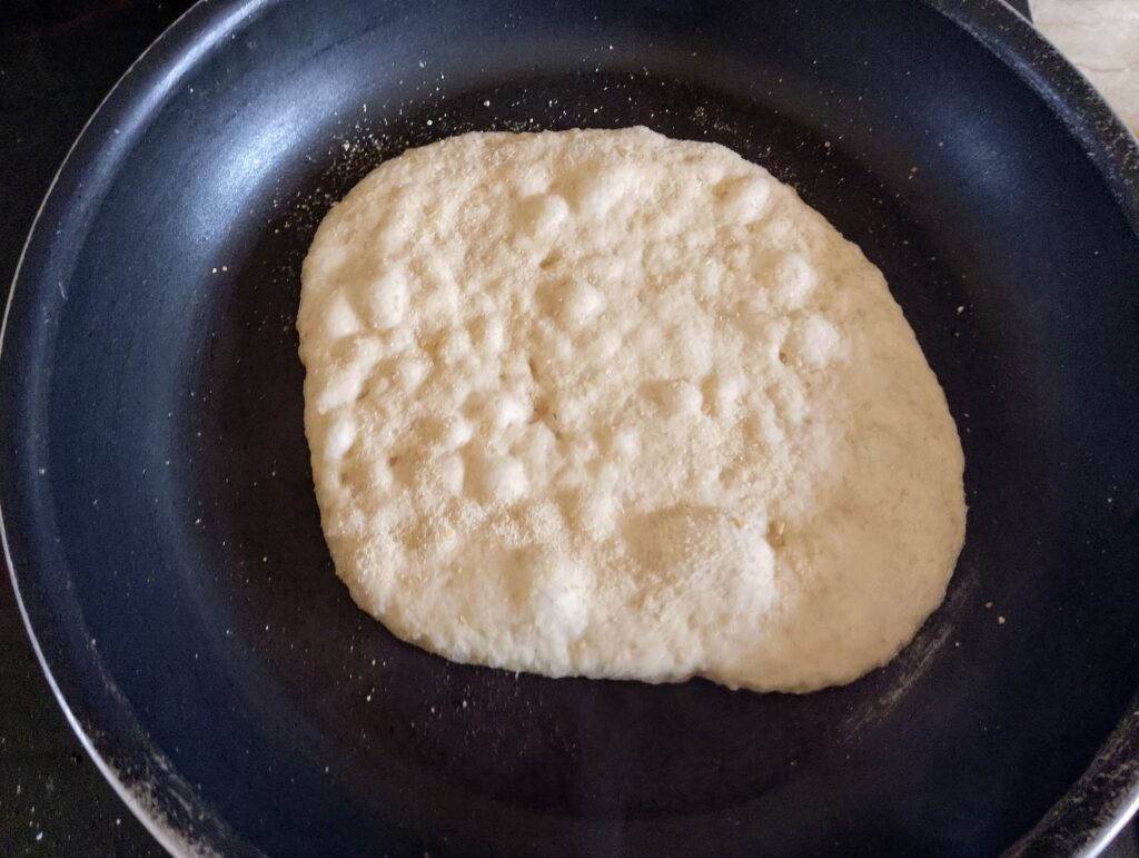 Cooking the sourdough naan in a hot skillet