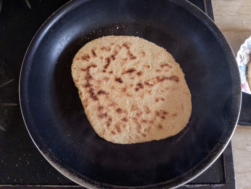 Flipping the naan to cook on the other side in the skilllet