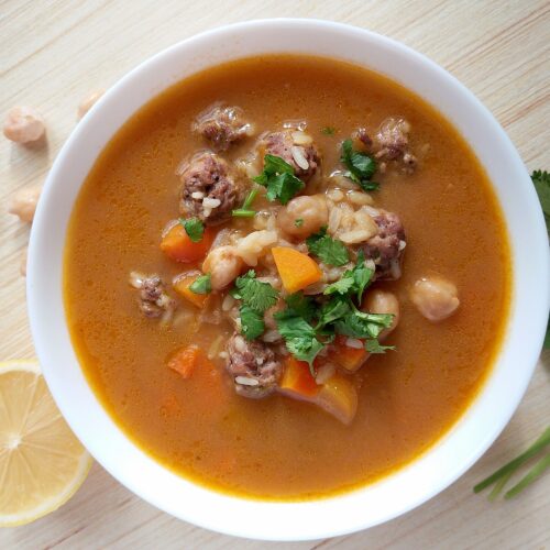 Turkish meatball soup in a bowl, garnished with chopped cilantro