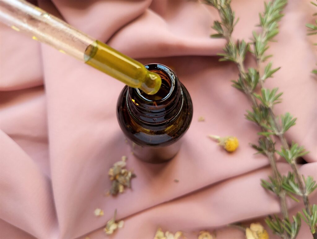 A dropper removing some of the DIY hair and scalp oil from amber bottle