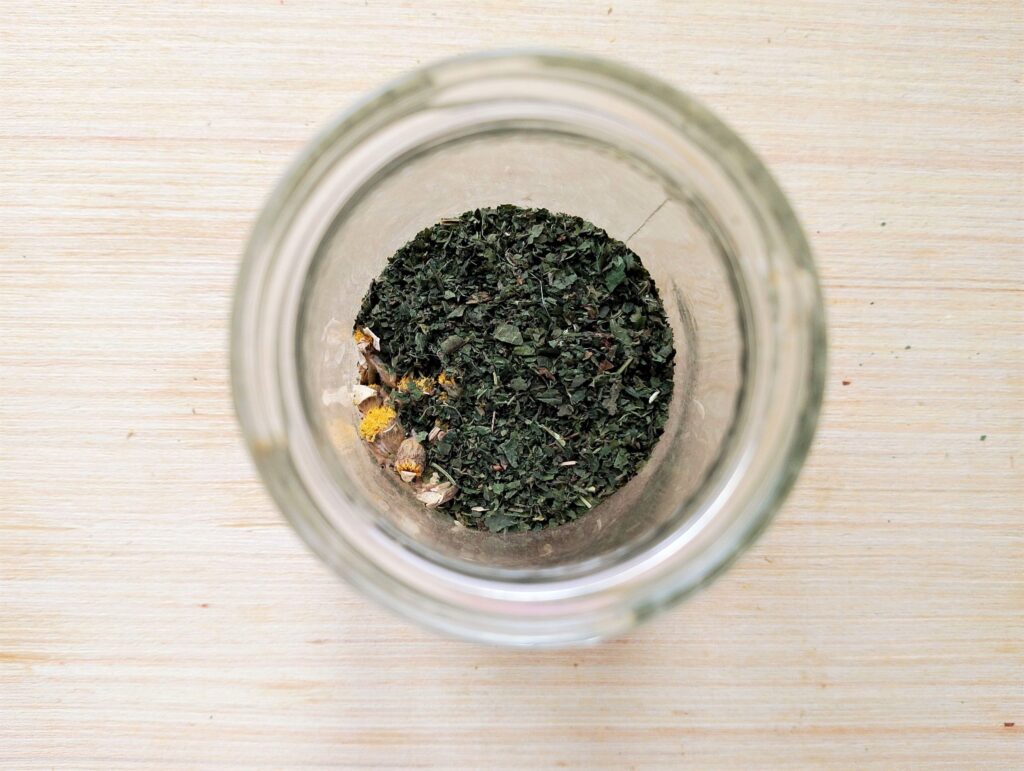 Placing crushed herbs in a small glass jar