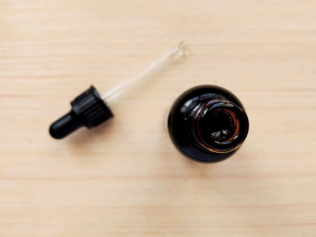 Pouring the finished DIY hair and scalp oil into an amber dropper bottle for long term storage