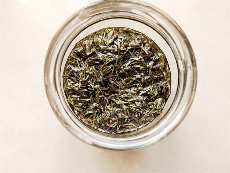 Pouring oil over the herbs in the jar
