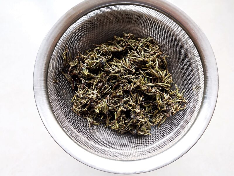 Straining out the spent herbs from the infused oil