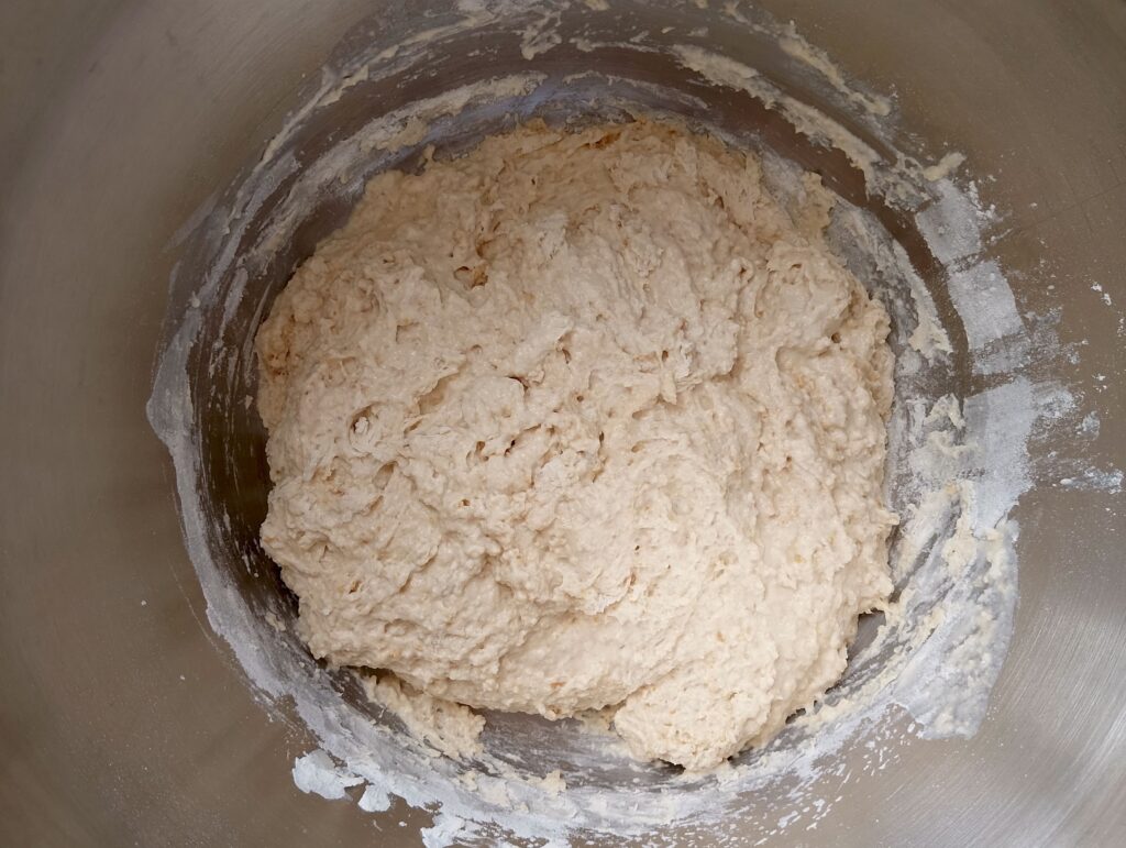 Adding flour into the water and starter mixture to make the shaggy dough
