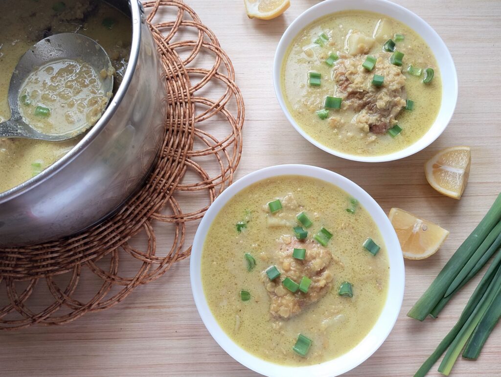 Serving the red lentil and chicken stew in bowls with a garnish of sliced green onions and a squeeze of lemon juice