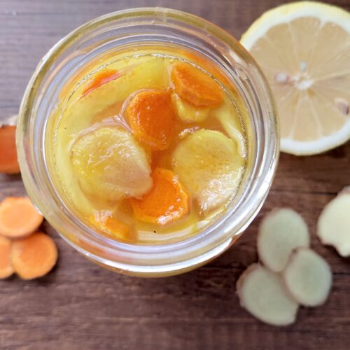 How to ferment honey: jar of lemon, ginger and turmeric honey on a wooden table
