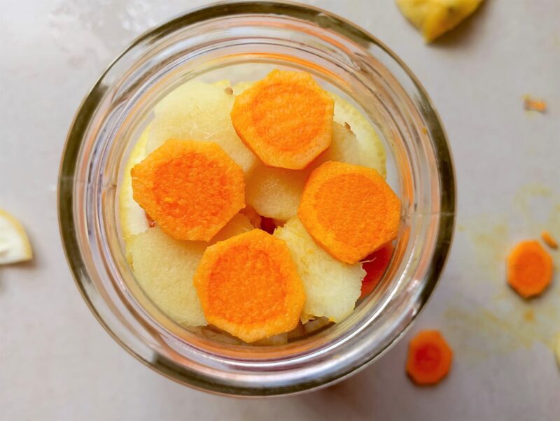 Layering sliced lemon, ginger and turmeric in a jar