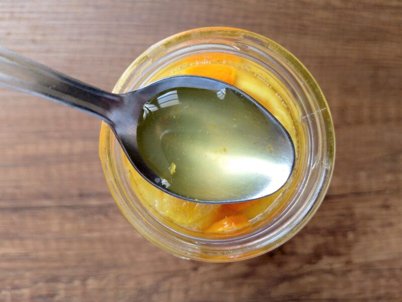 A teaspoon scooping some of the lemon, ginger and turmeric fermented honey from the jar