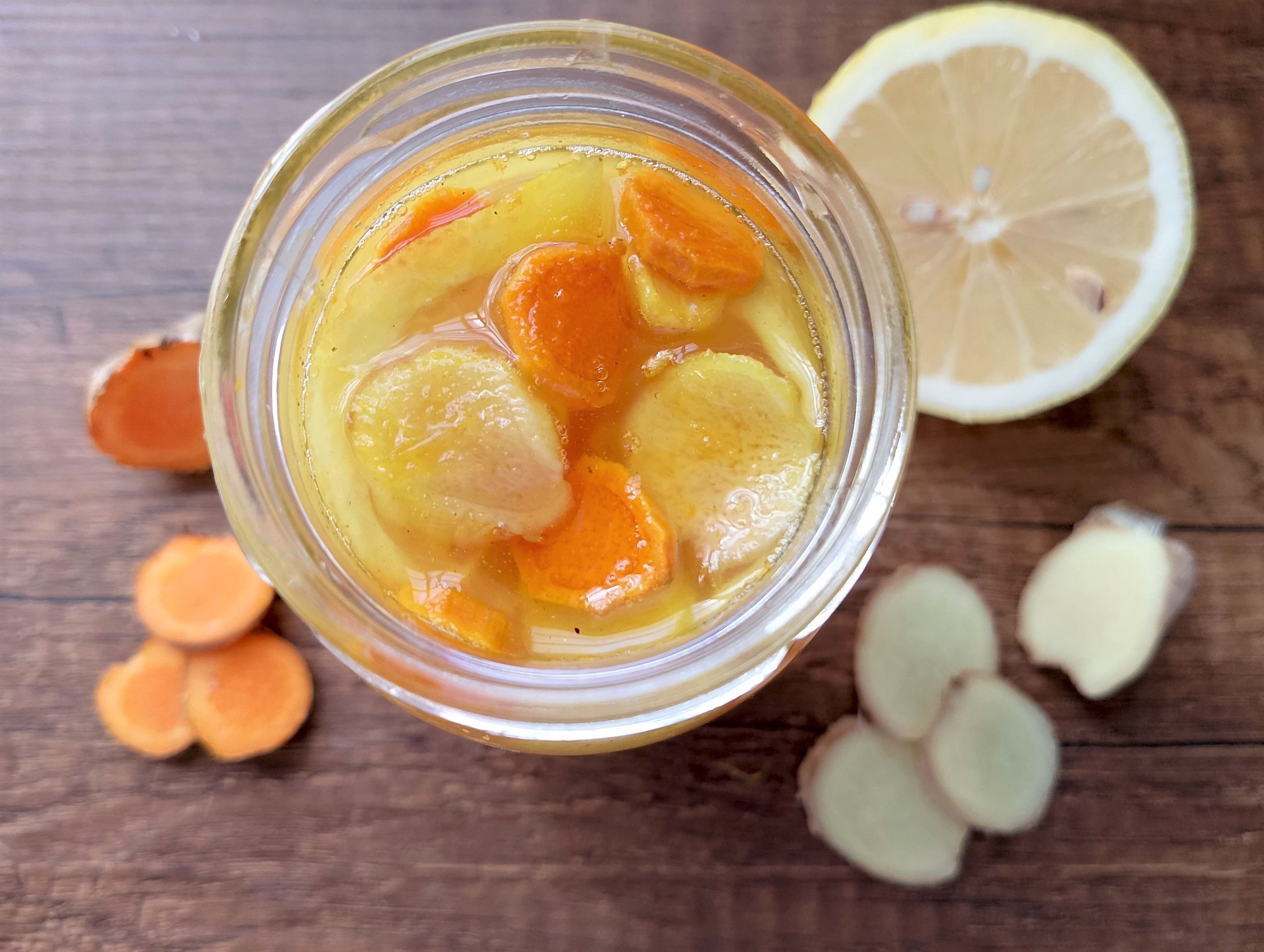 How to ferment honey: jar of lemon, ginger and turmeric honey on a wooden table