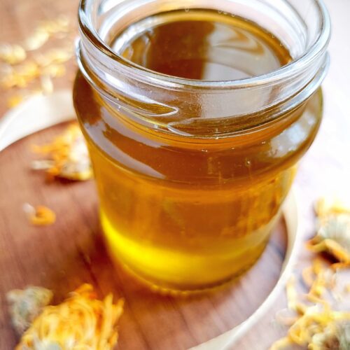 How to make calendula oil: jar of calendula oil on wooden table