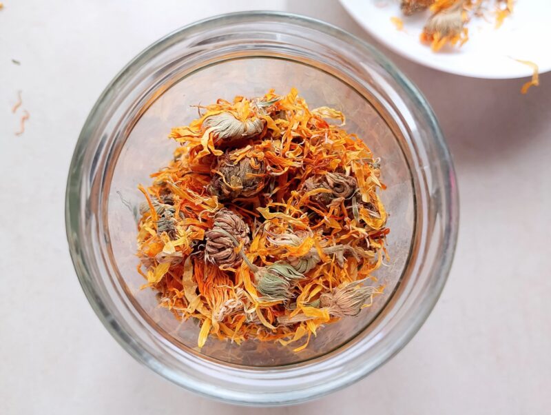 Filling a jar with dried calendula flowers