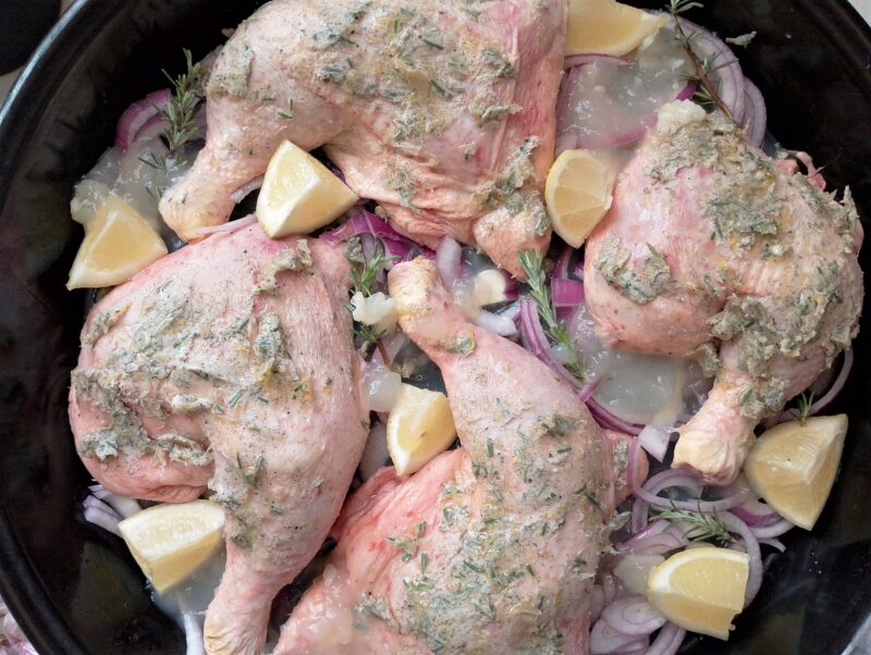 Adding chicken broth to the pan with marinated chicken legs