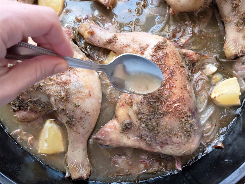 Woman basting rosemary lemon chicken legs in the pan