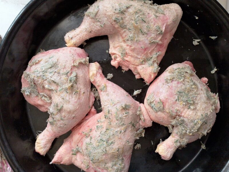 Rubbing marinade onto chicken legs in a baking pan