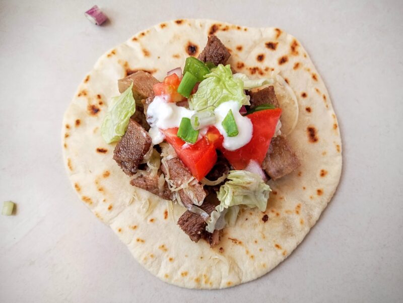 Beef tongue taco with lettuce, salsa, and a drizzle of sour cream