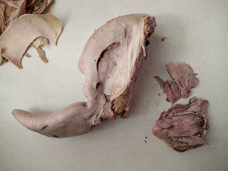 Cutting off rough pieces of meat on the underside of beef tongue