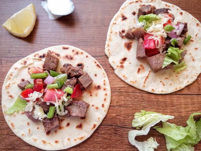 Beef tongue tacos with lettuce, salsa, and cheese on wooden table