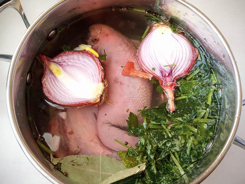 Beef tongue in pot with aromatics and water, ready to be cooked