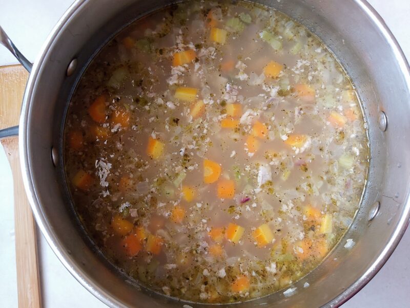 Adding cooked gizzards to soup in pot