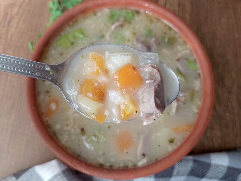 Spoon lifting some of the chicken gizzard soup from the bowl