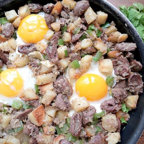 Chicken hearts hash in skillet with fresh parsley on the side