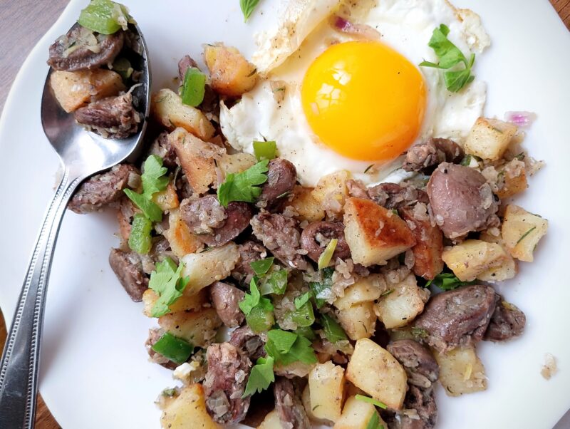 Chicken hearts hash, served on a plate with fried egg on the side