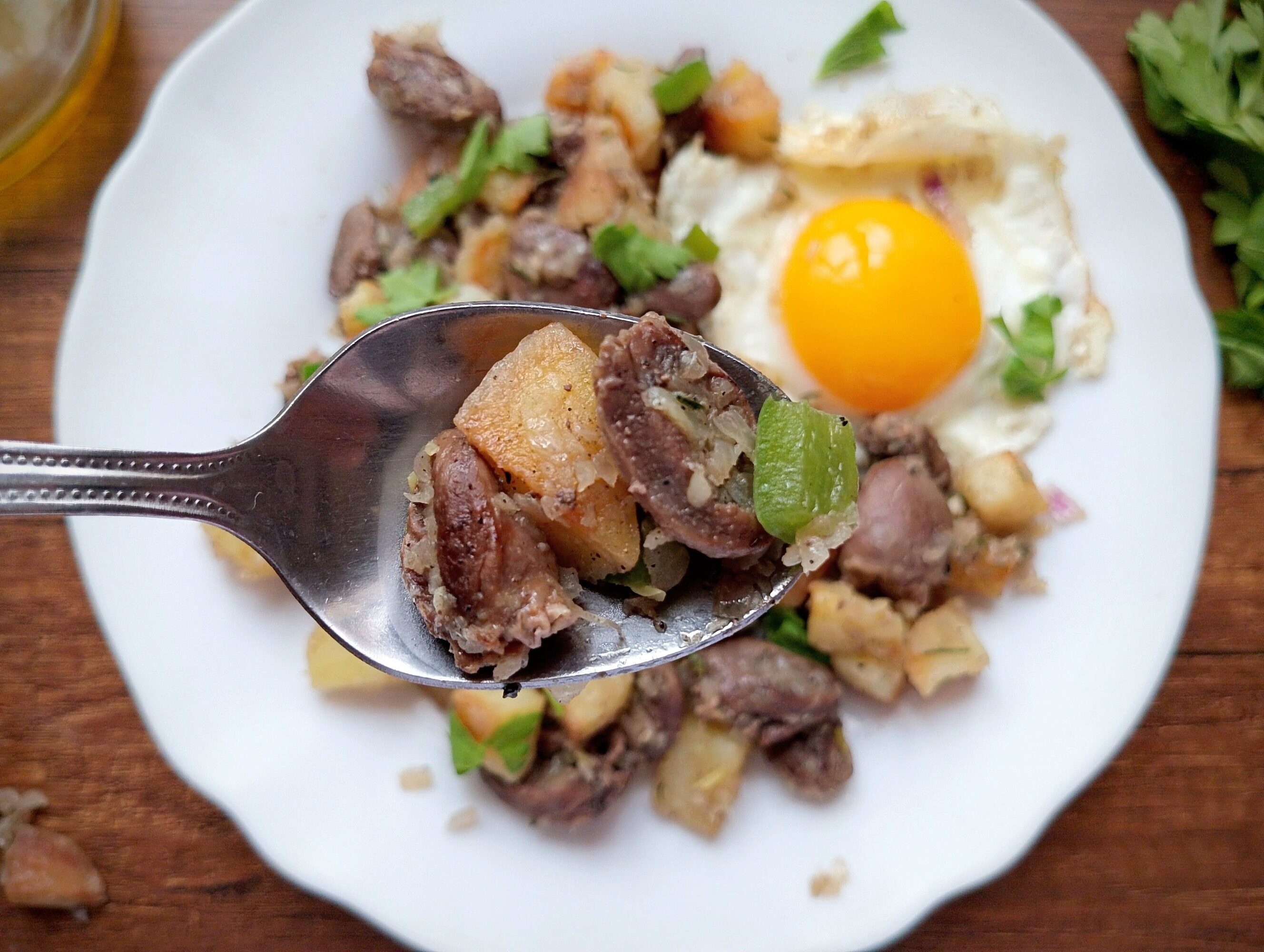 Spoon lifting some of the chicken hearts hash off a plate