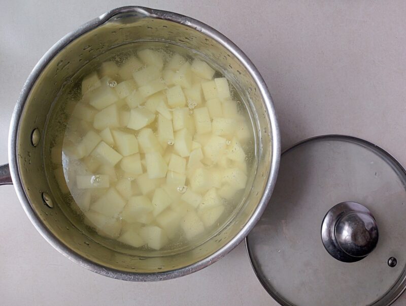 Peeled and cubed potatoes in pot, covered in water and ready for cooking