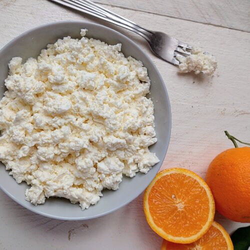 Quark cheese in bowl with fresh oranges on the side