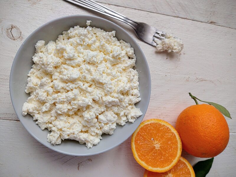 Quark cheese in bowl with fresh oranges on the side