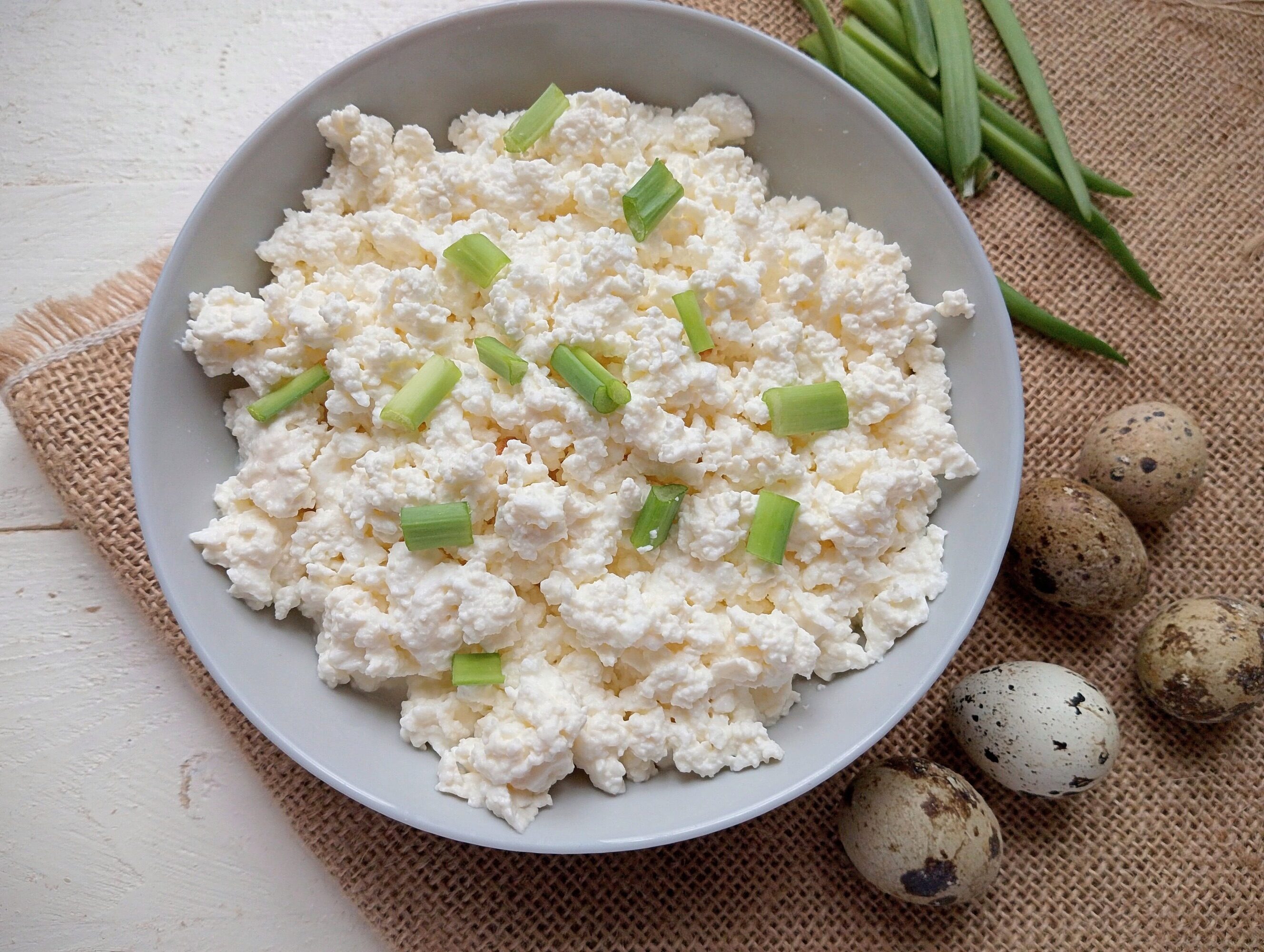 Quark cheese served in bowl, garnished with sliced green onions