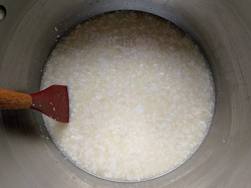 Warming clabbered milk in pot over low heat to tighten the curds