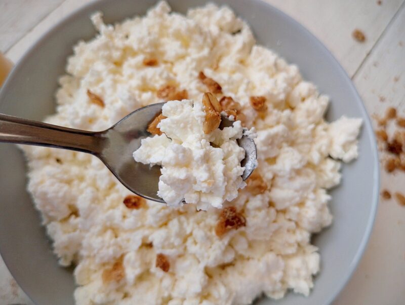 Spoon lifting some quark cheese from a bowl