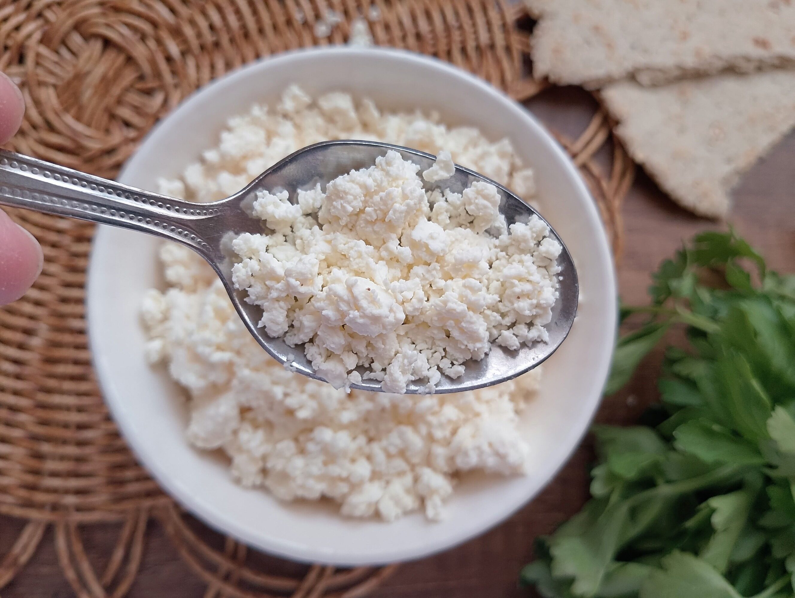 Spoon lifting farmer's cheese from a bowl