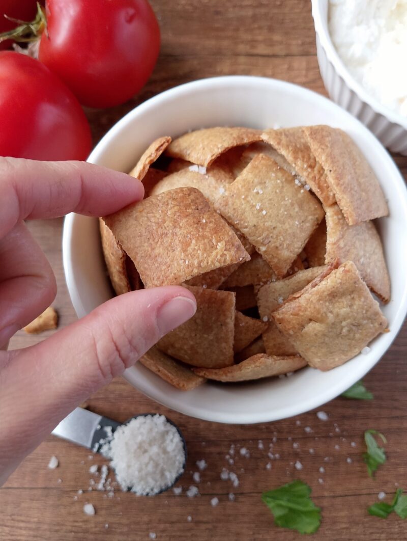 Hand reaching for a sourdough cracker in a bowl