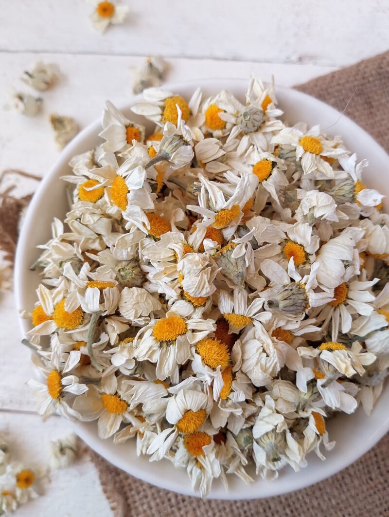 Bowl of dried chamomile flowers on table