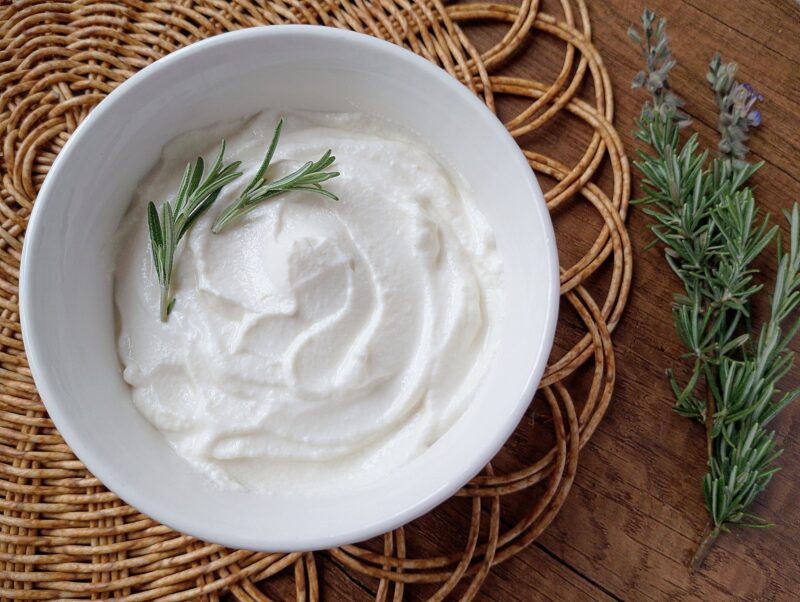 How to make ricotta from whey: whey ricotta cheese in a bowl, garnished with sprigs of fresh rosemary