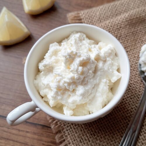 Kefir cheese in serving cup with a teaspoon of cheese on the side