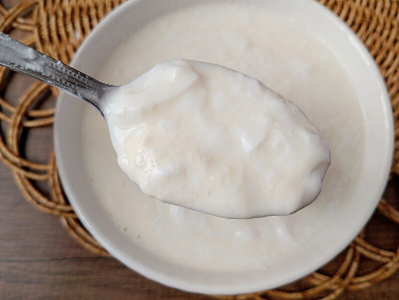 Spoon lifting clabbered milk from a bowl