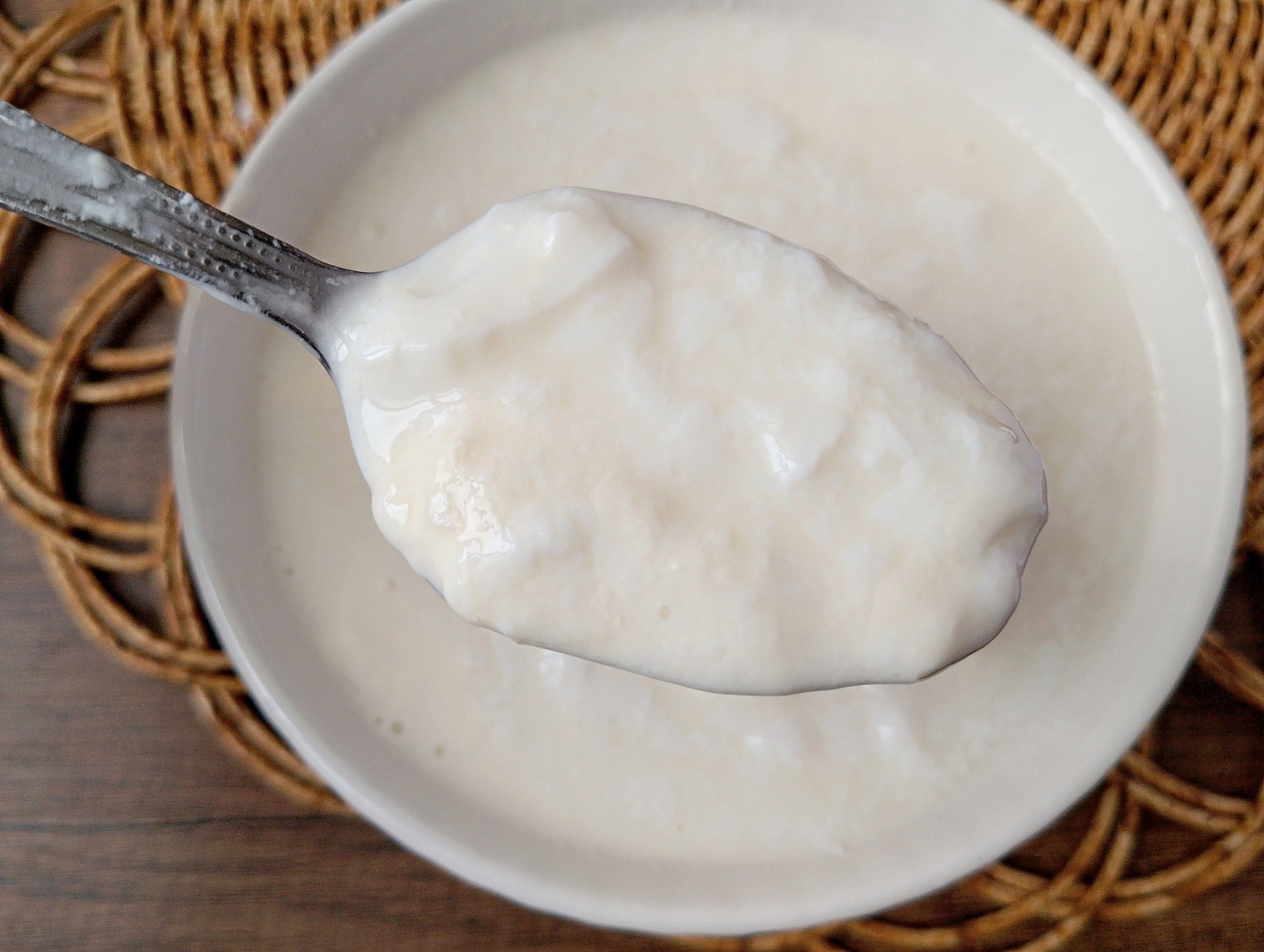 Spoon lifting clabbered milk from a bowl