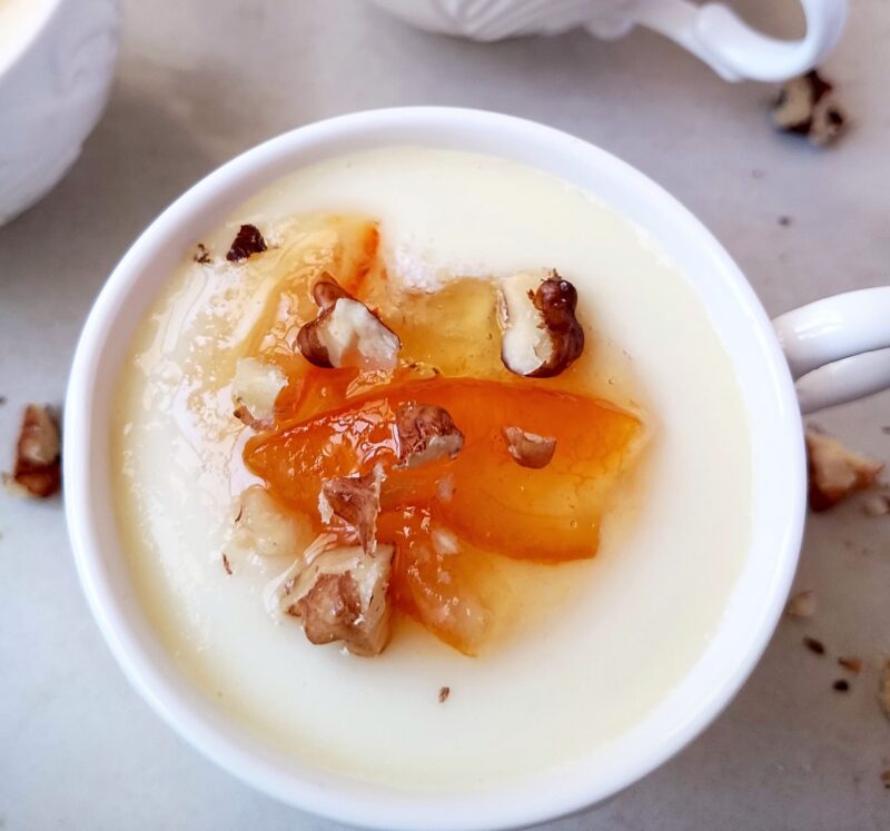 Topping junket in cup with homemade marmalade and chopped walnuts