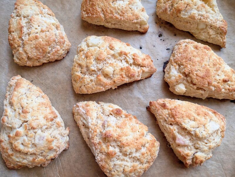 Freshly baked peaches and cream sourdough scones on lined baking sheet