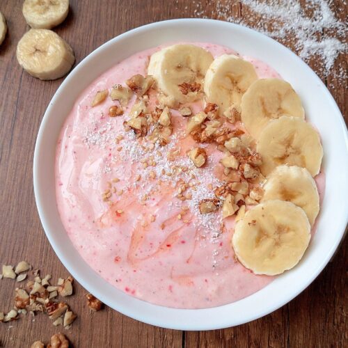 Healthy smoothie bowl with cottage cheese and kefir, topped with sliced bananas and chopped nuts