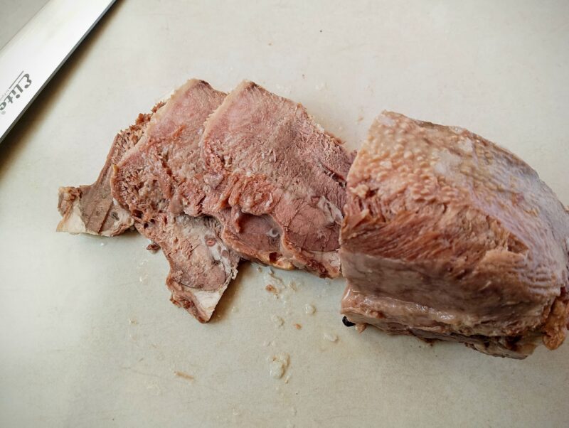Slicing pressure cooked beef tongue on counter
