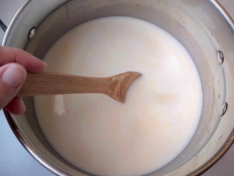 Stirring rennet into milk in pot