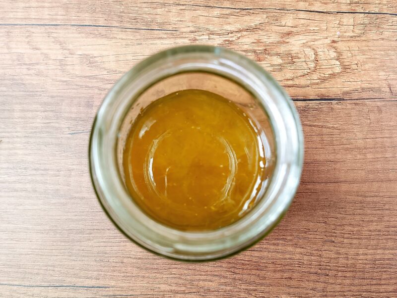 Adding calendula infused olive oil to melted tallow and beeswax in jar