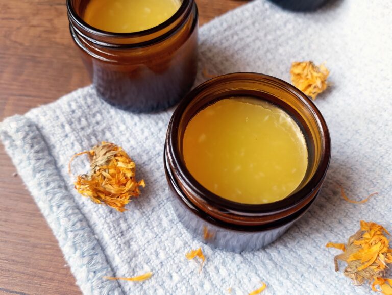 Calendula balm in amber jars with dried calendula flowers scattered around