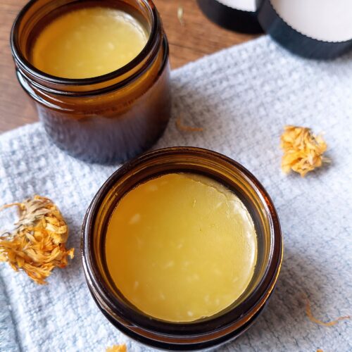 Calendula balm in amber jars with calendula flowers scattered around