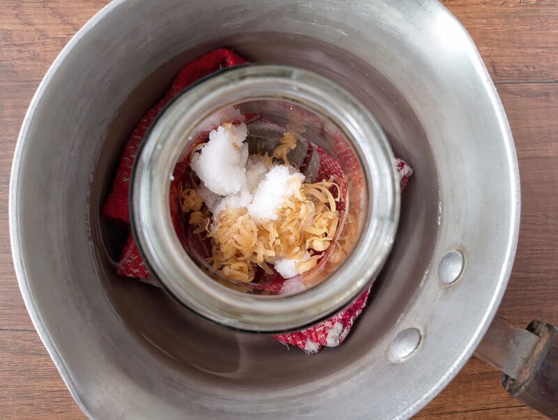 Melting tallow and grated beeswax in homemade double boiler to make balm